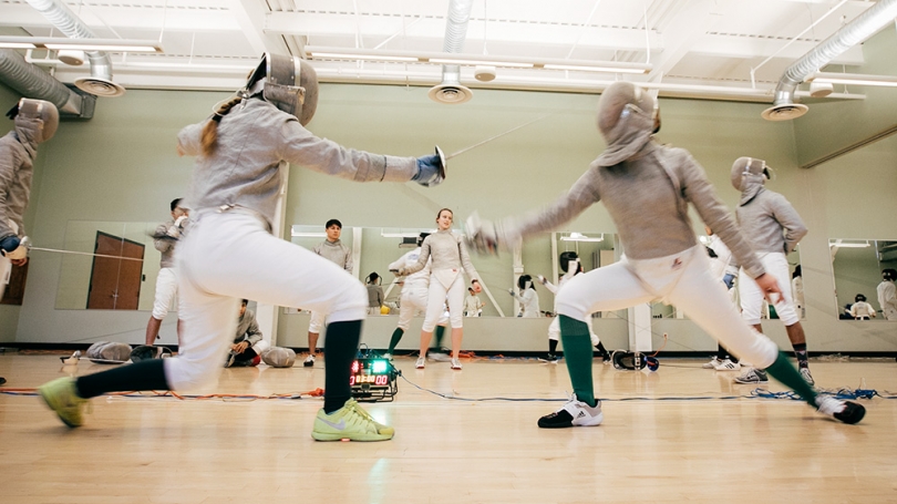 Two women fence during a fencing match.